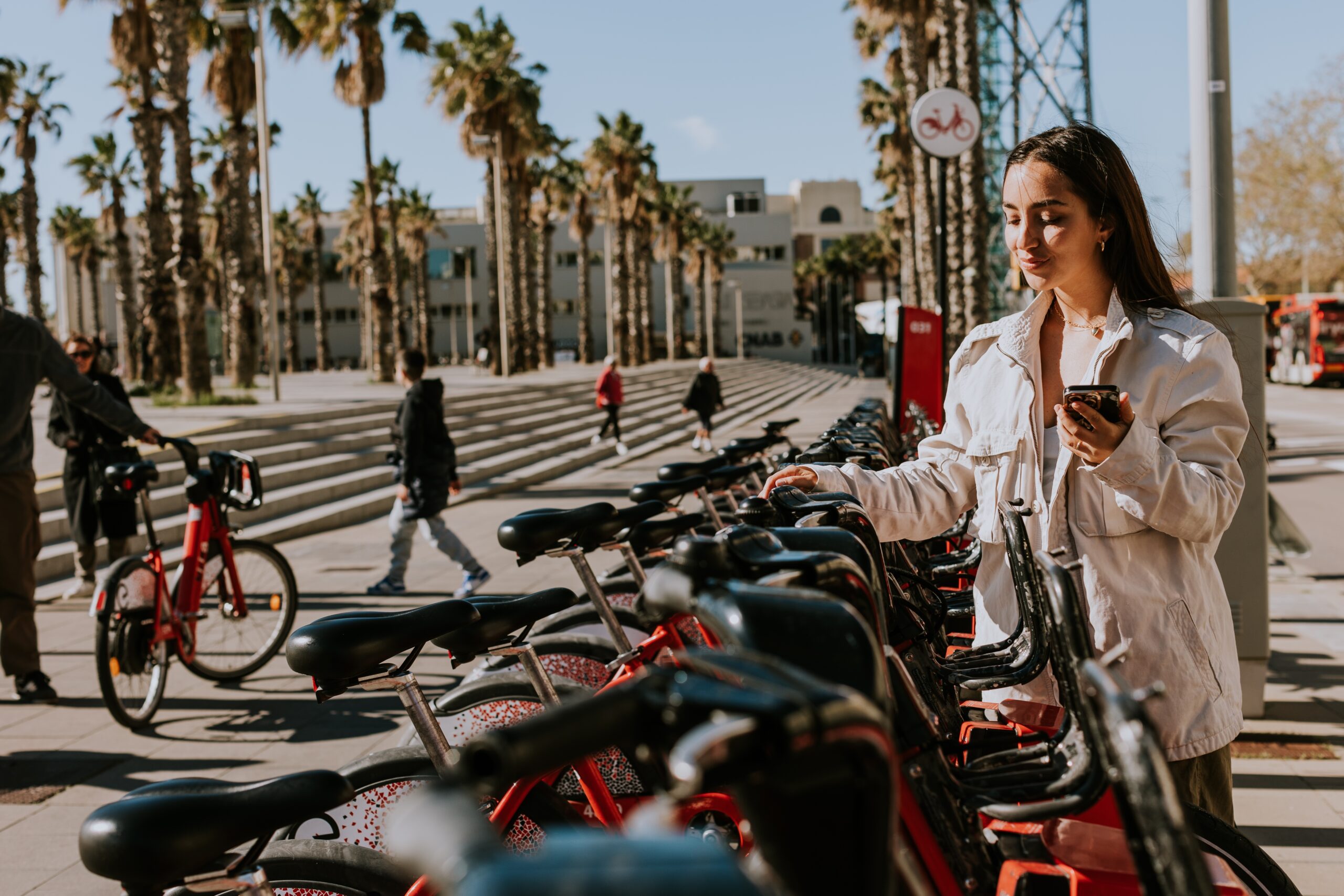 Young,Woman,Stands,By,A,Row,Of,Red,Bikes,In